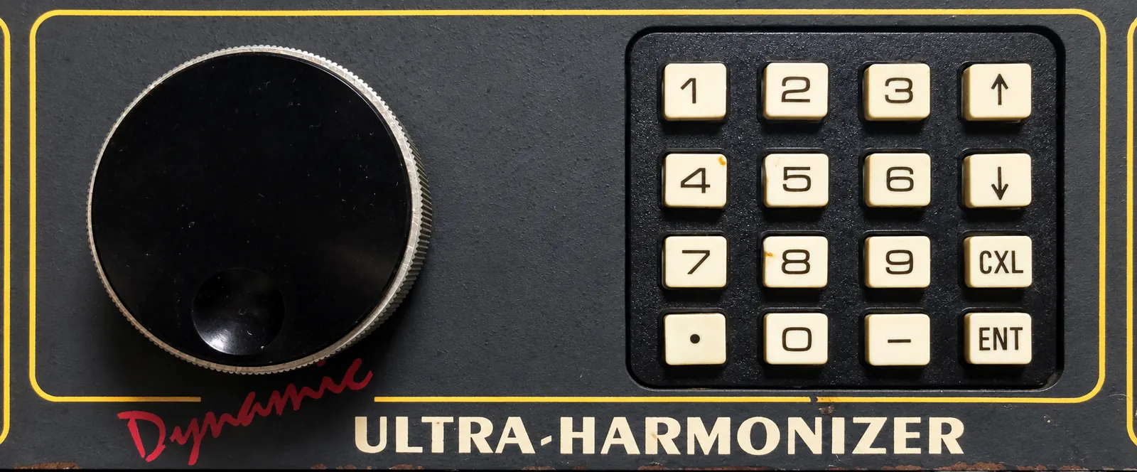 A black knob with a silver rim and a 4 × 4 keypad (1–9, 0, decimal point, minus, arrows, CXL and ENT). Below are red Dynamic script and ULTRA-HARMONIZER lettering.