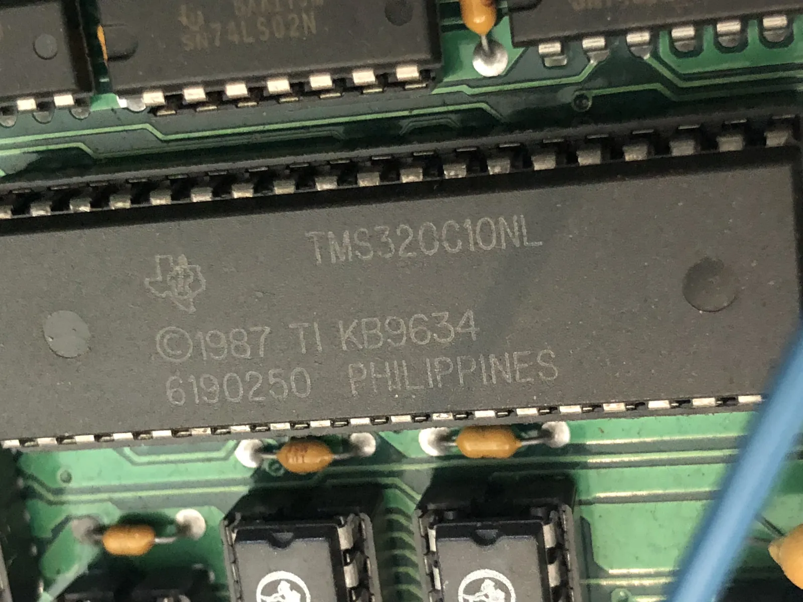 A long chip with the TI logo and TMS320C10NL marking.